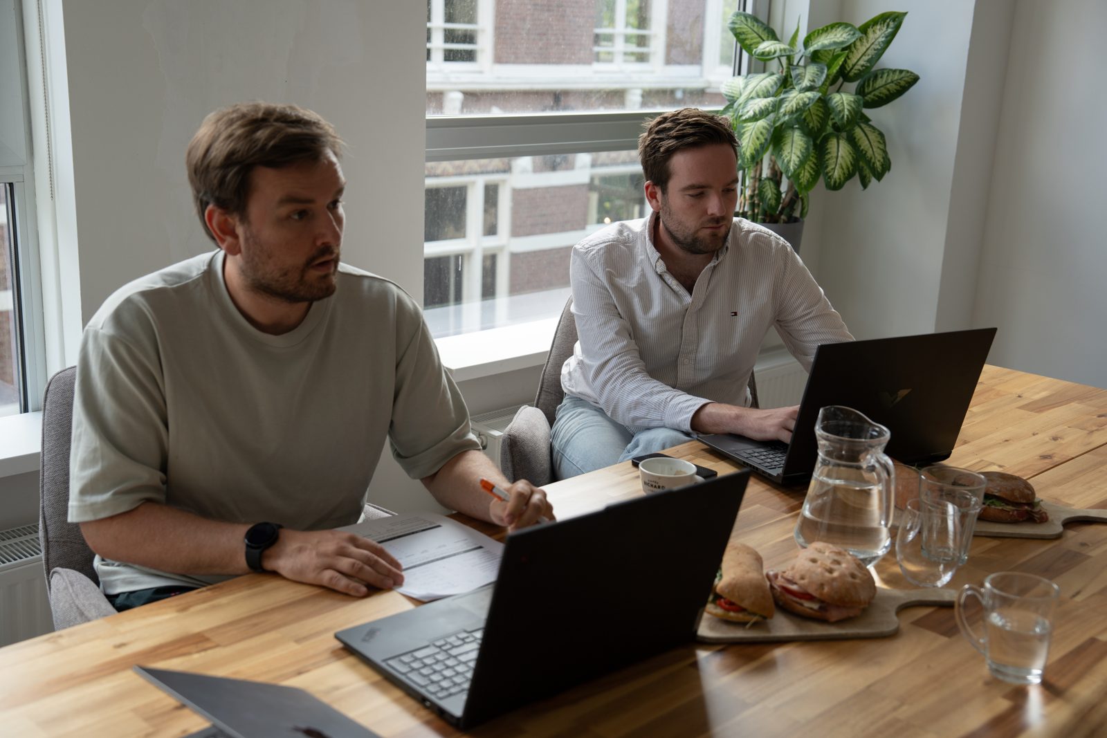 Twee mensen van Webnexus werken aan tafel met laptops