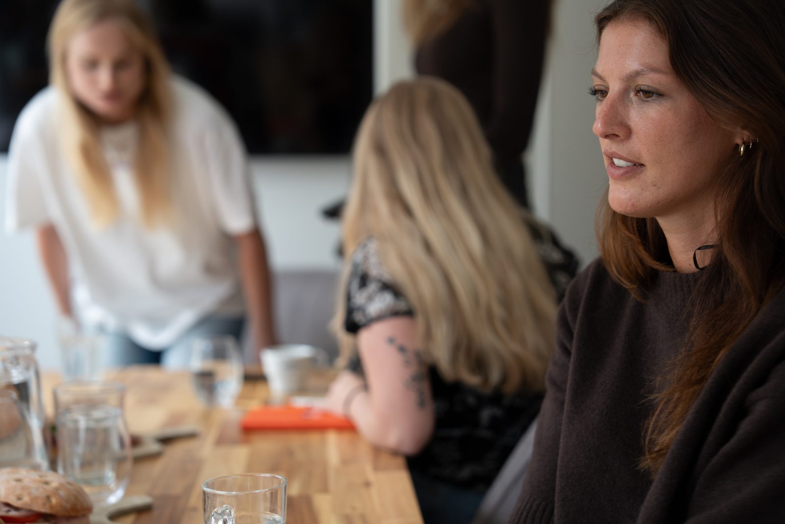 Drie mensen van een marketingbureau in gesprek aan een vergadertafel tijdens een Cut The Crap-sessie