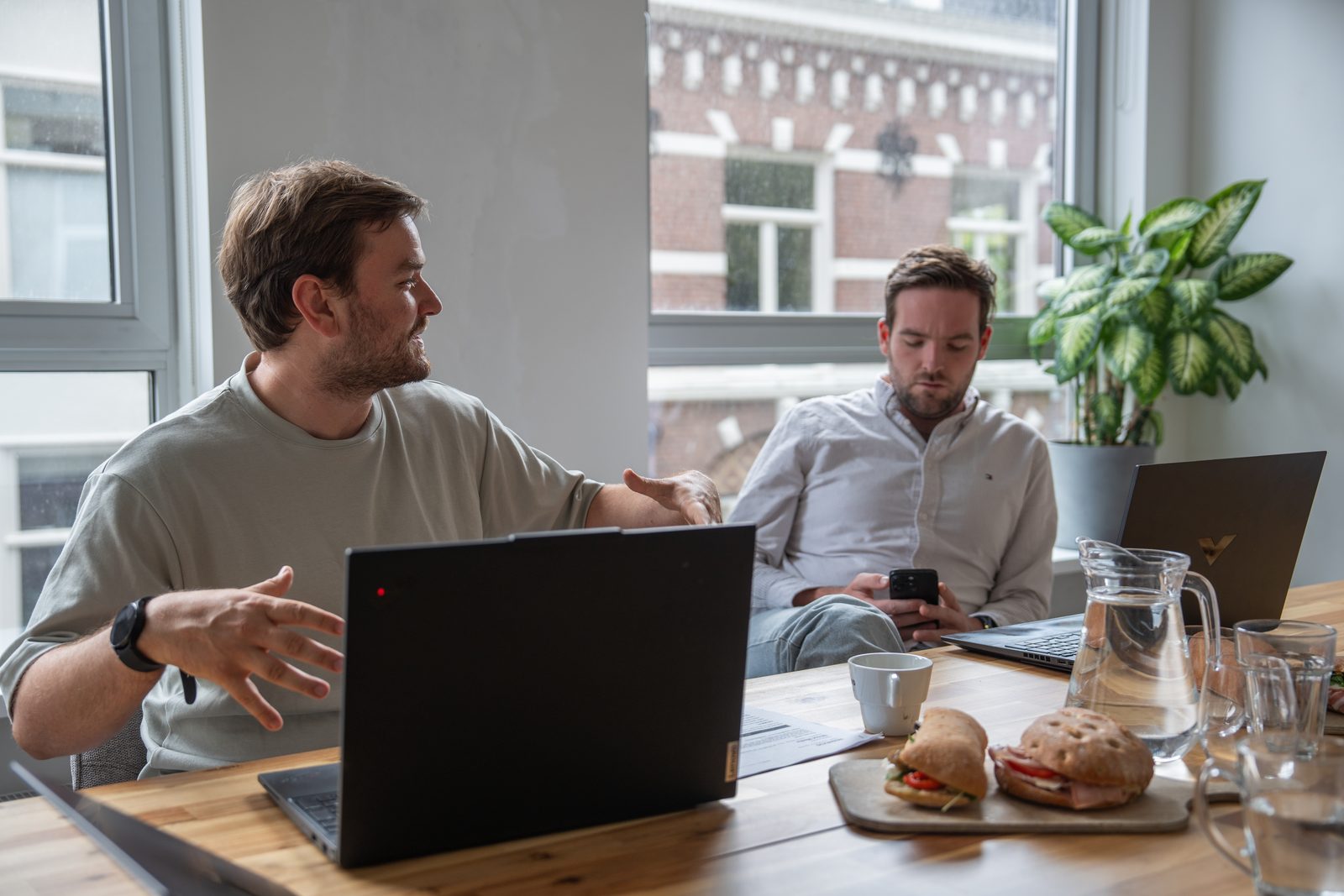 Boyd van Webnexus legt aan tafel iets uit achter een laptop, Peter kijkt mee