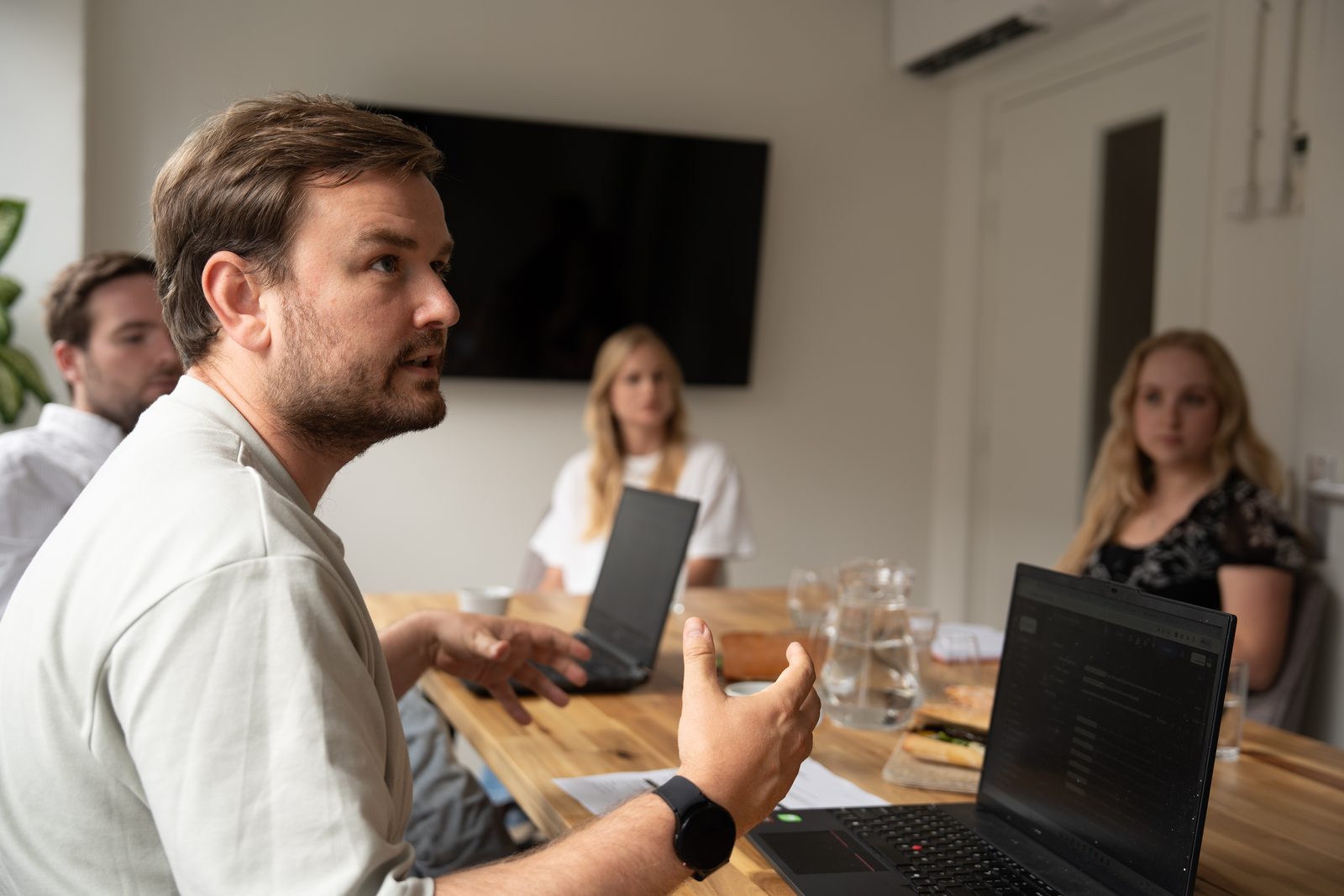 Boyd Belshof legt aan tafel uit hoe een team zijn werkprocessen vastlegt, met laptops en koffie op tafel